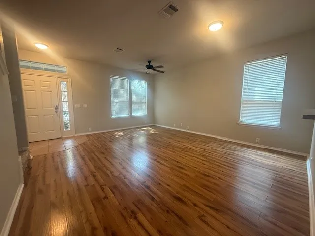 an empty room with wooden floor and windows