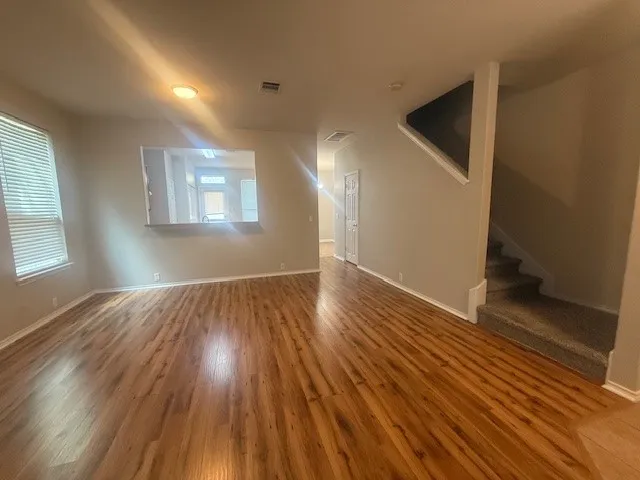 an empty room with wooden floor and windows