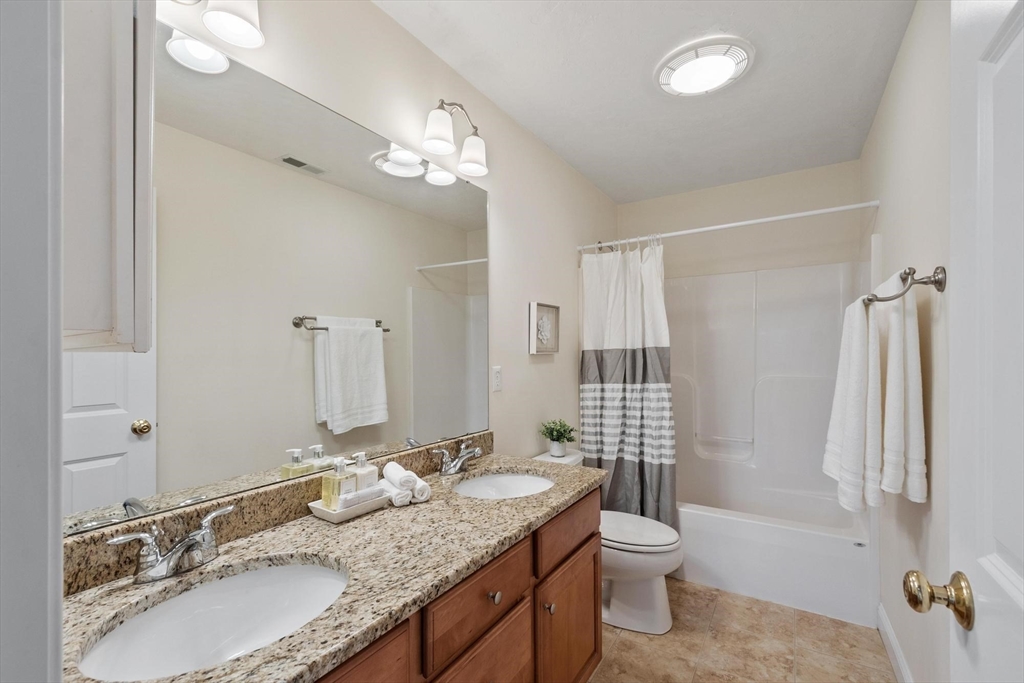 4 Henley Road Acton, MA 01720 - Photo 28 of 32 a bathroom with a granite countertop double vanity sinks a mirror and a shower