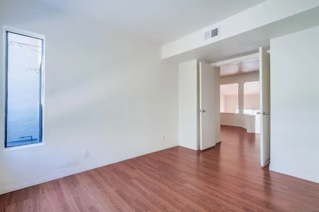 a view of an empty room with wooden floor and a window