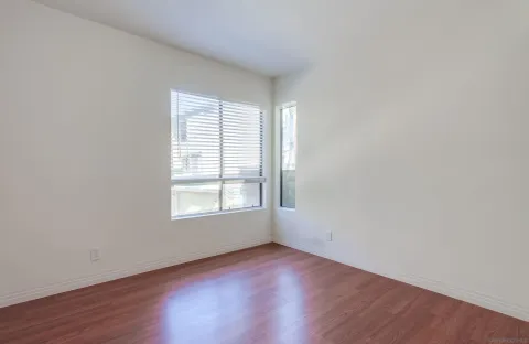 an empty room with wooden floor and window