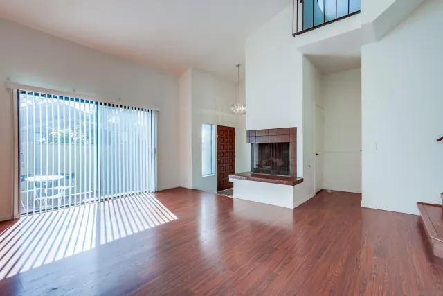 an empty room with wooden floor fireplace and windows