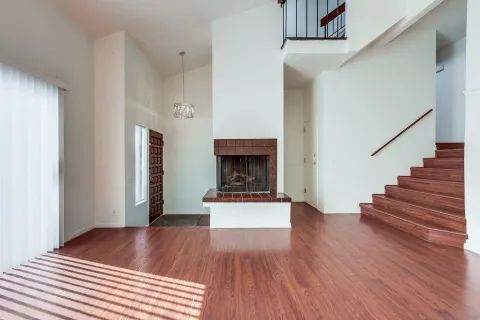 a view of a livingroom with wooden floor and a fireplace