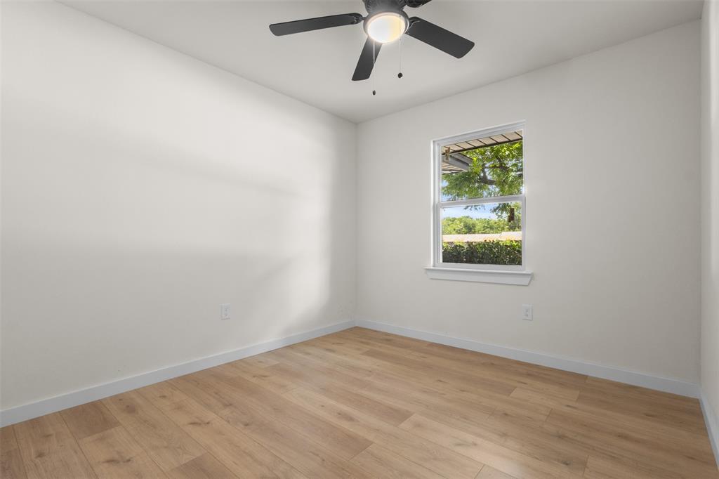 907 Pinson Road Forney, TX 75126 - Photo 17 of 35 Room featuring a ceiling fan with integrated lighting, a window with exterior views, wood-finish flooring, and white baseboards
