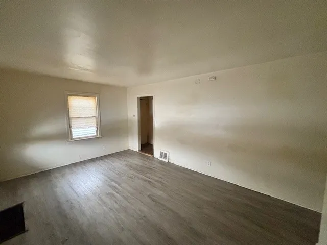 an empty room with wooden floor and window