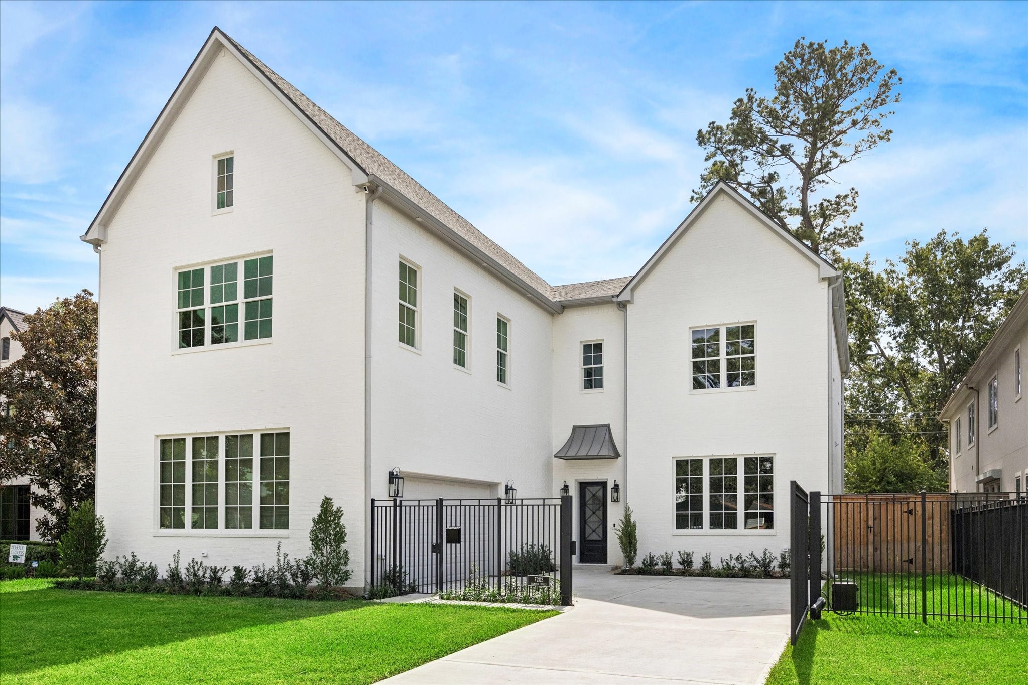 a view of a white house next to a yard with big trees
