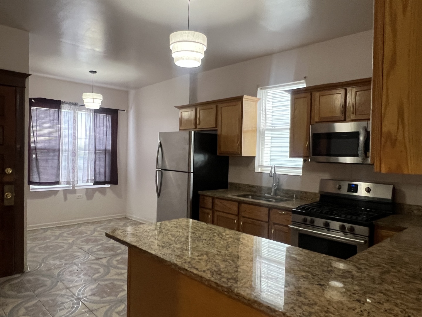 1921 North Pulaski Road, Unit 1 Chicago, IL 60639 - Photo 6 of 16 a kitchen with stainless steel appliances granite countertop a sink refrigerator stove and microwave