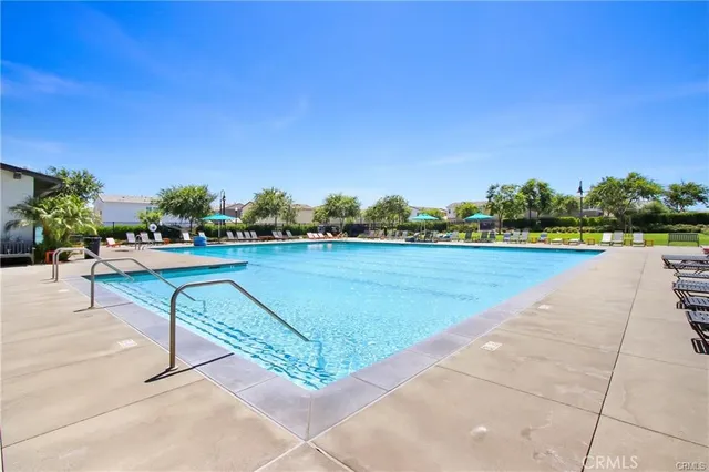 a view of swimming pool with seating space and trees in the background