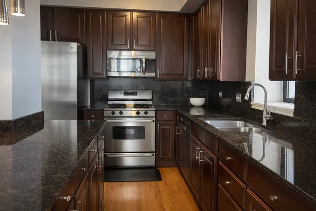 a kitchen with stainless steel appliances granite countertop a stove a sink and a microwave