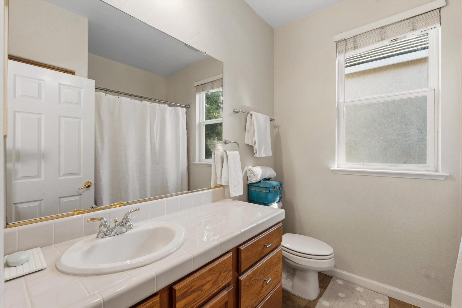 6503 Turnstone Way Rocklin, CA 95765 - Photo 29 of 42 a bathroom with a sink a toilet and shower curtain