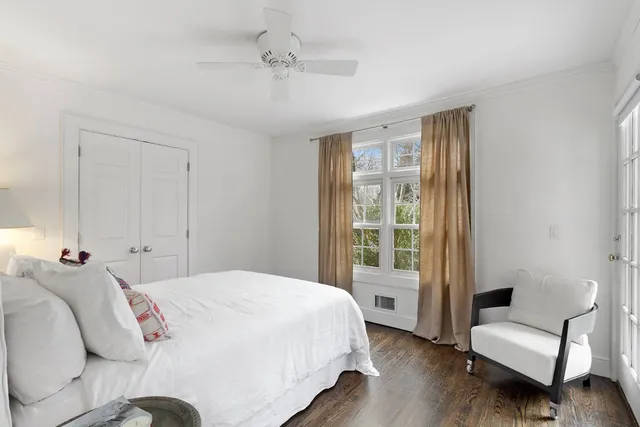a bedroom with a bed wooden floor and a large window