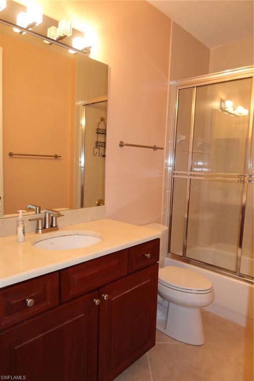 7168 Lemuria Circle, Unit 1701 Naples, FL 34109 - Photo 28 of 39 Bathroom featuring a wood-finish vanity with a light-toned countertop, an undermount sink, and a brushed nickel faucet