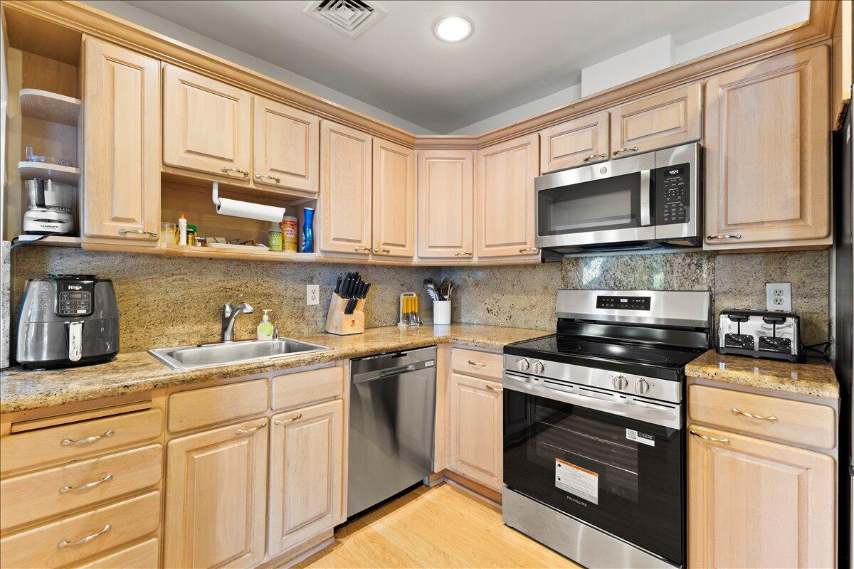 233 Rio Vista Circle Atlantis, FL 33462 - Photo 16 of 38 a kitchen with stainless steel appliances granite countertop a stove top oven a sink dishwasher and white cabinets with wooden floor
