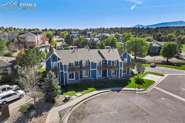a view of a big house with a big yard and large trees