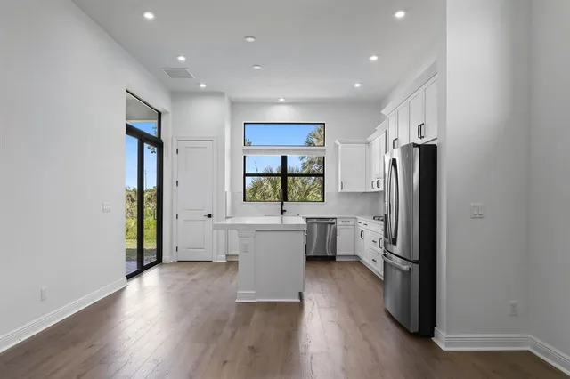 a kitchen with a refrigerator a sink and wooden floor