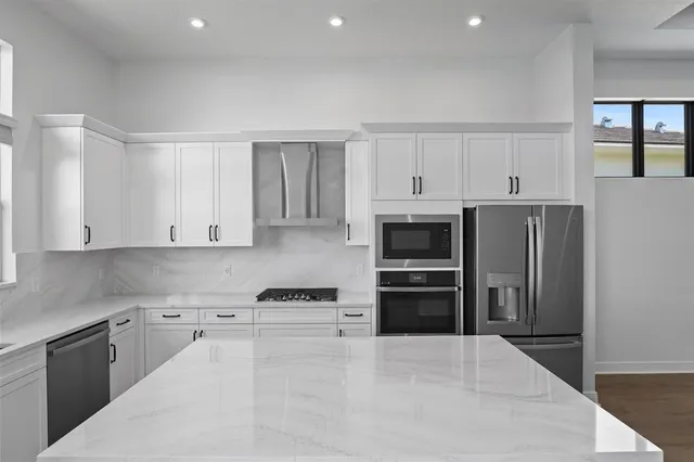 a kitchen with stainless steel appliances a stove a refrigerator a sink and white cabinets