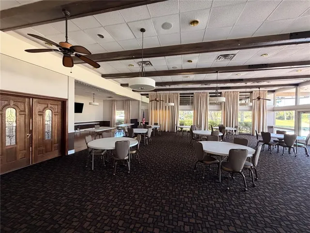 a room with lots of tables a large window and chairs