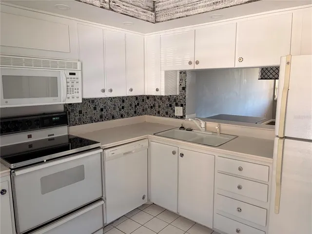 a kitchen with white cabinets and sink