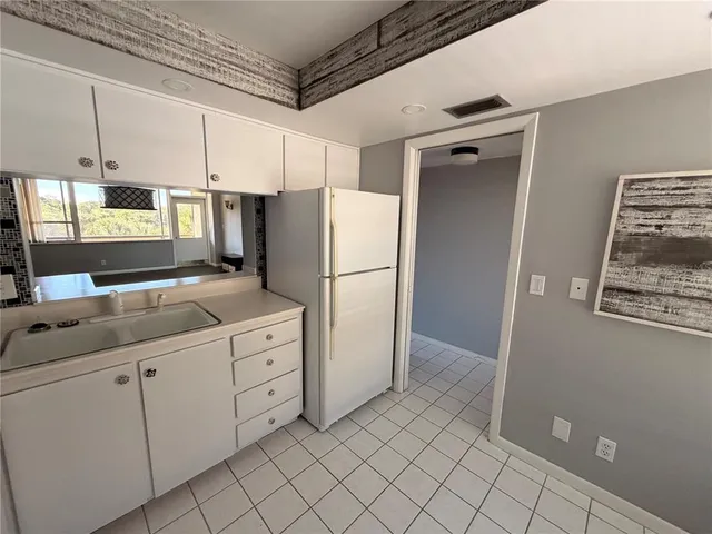 a kitchen with white cabinets and refrigerator