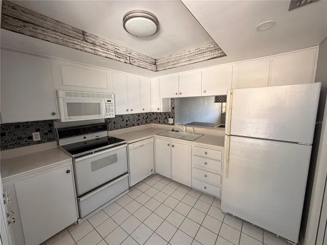 a kitchen with white cabinets and white appliances