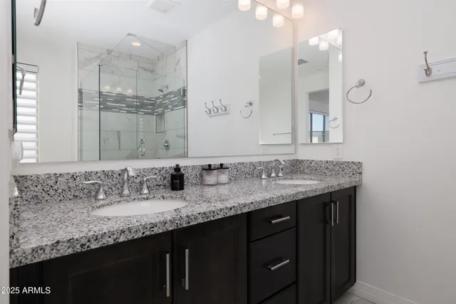 a bathroom with a granite countertop sink a large mirror and a shower