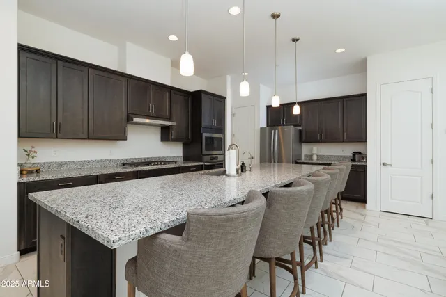 a kitchen with stainless steel appliances granite countertop a kitchen island a stove a sink a oven a dining table and chairs