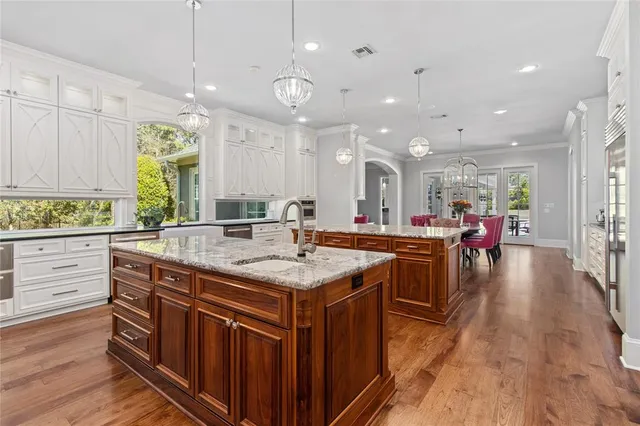 a kitchen with stainless steel appliances granite countertop a stove and a large island with wooden floor