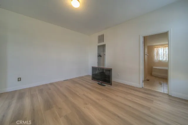 a view of an empty room with wooden floor and windows