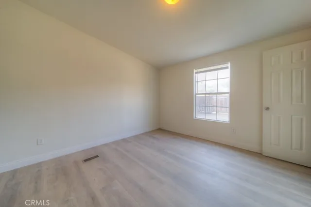 a view of an empty room with wooden floor and a fireplace
