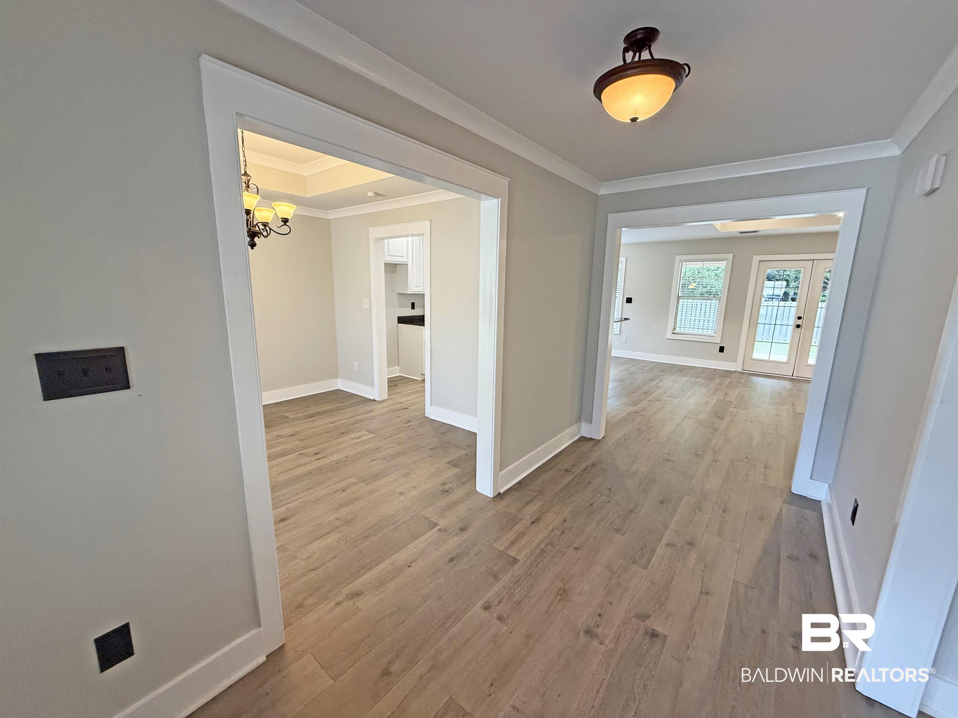 22023 Garland Loop Silverhill, AL 36576 - Photo 4 of 33 Hall featuring crown molding, a chandelier, and light wood-style floors