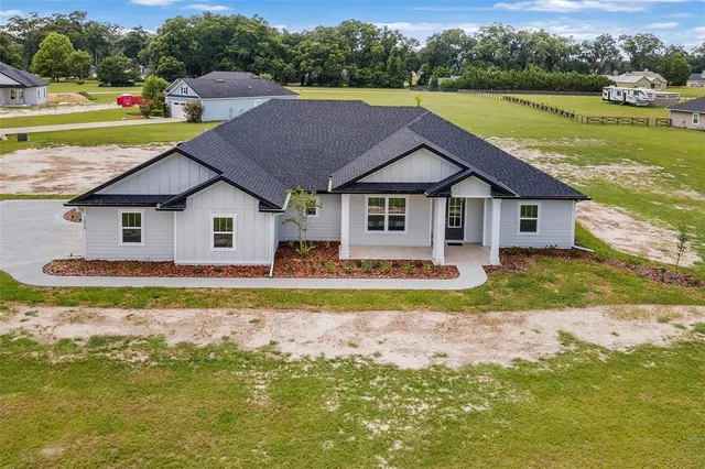 a front view of a house with a garden and lake view