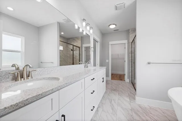 a spacious bathroom with a granite countertop sink a toilet a mirror and shower