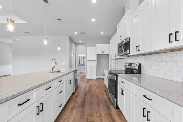 a large kitchen with stainless steel appliances lots of counter space and wooden floors