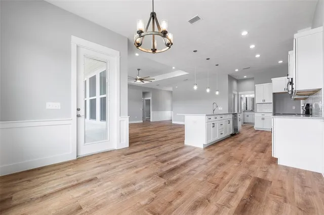 a view of a kitchen with kitchen island stainless steel appliances wooden floor cabinets and a dining table