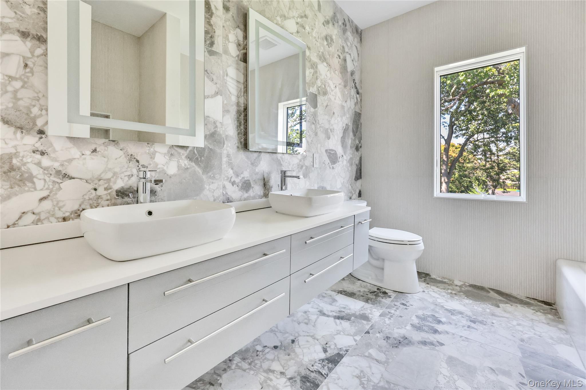 8 Sealy Drive Lawrence, NY 11559 - Photo 21 of 49 Bathroom with plenty of natural light, double vanity, light marble finish floors, a tub, and tile walls