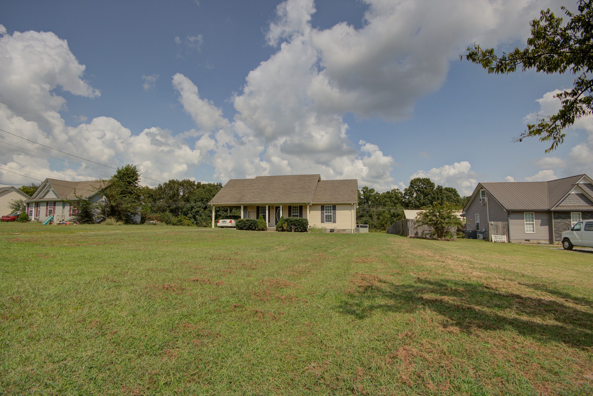 a view of a big house with a big yard and large trees