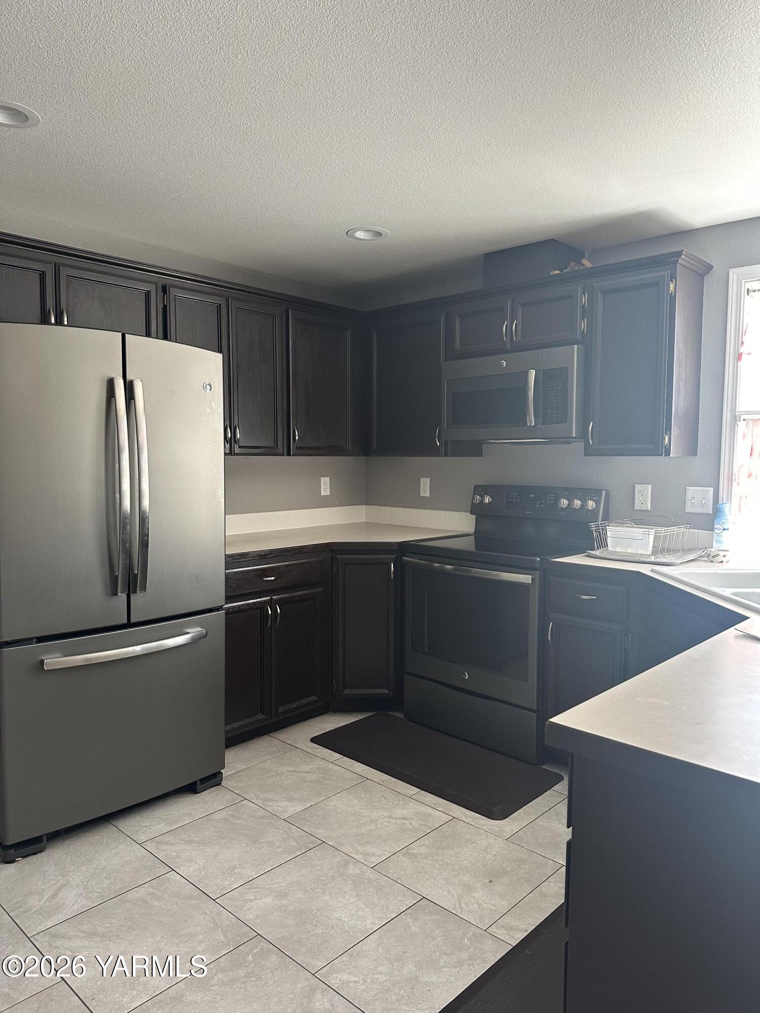 514 Cascade Avenue Moxee, WA 98936 - Photo 6 of 25 a kitchen with stainless steel appliances a refrigerator sink and cabinets