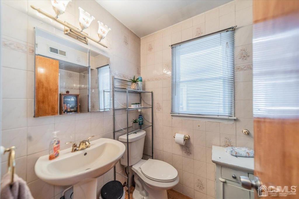 454 Mitchell Place Perth Amboy, NJ 08861 - Photo 12 of 36 a bathroom with a toilet a sink and mirror
