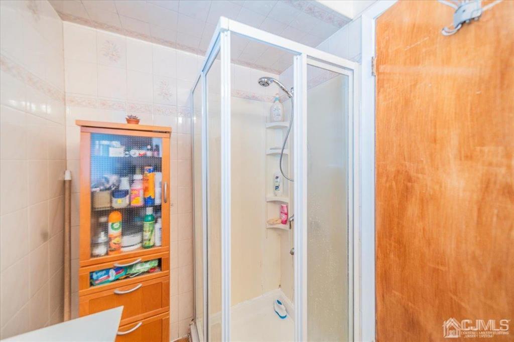 454 Mitchell Place Perth Amboy, NJ 08861 - Photo 13 of 36 a bathroom with a glass shower door and a glass door