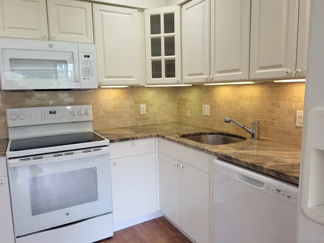 a kitchen with granite countertop white cabinets and a stove