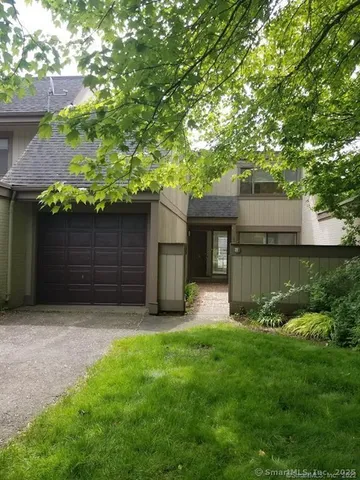 a view of house with yard and a large tree