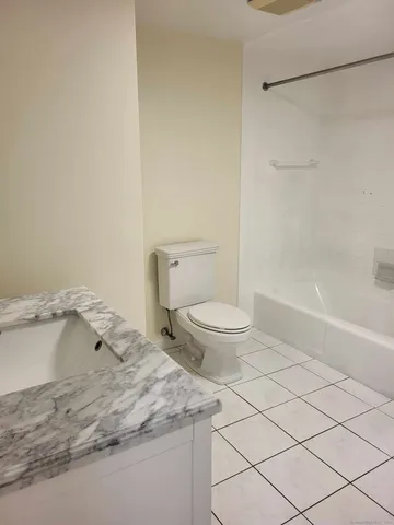 a bathroom with a granite countertop sink and a toilet