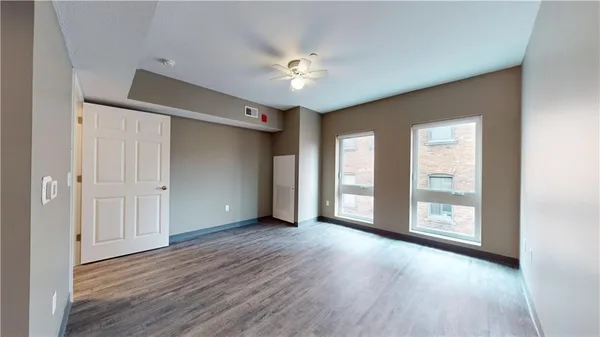 a view of an empty room with a window and wooden floor