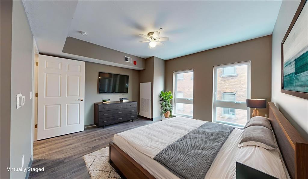 1450 Fifth Avenue, Unit 305 Pittsburgh, PA 15219 - Photo 9 of 22 a bedroom with a large bed a flat tv screen and a chandelier