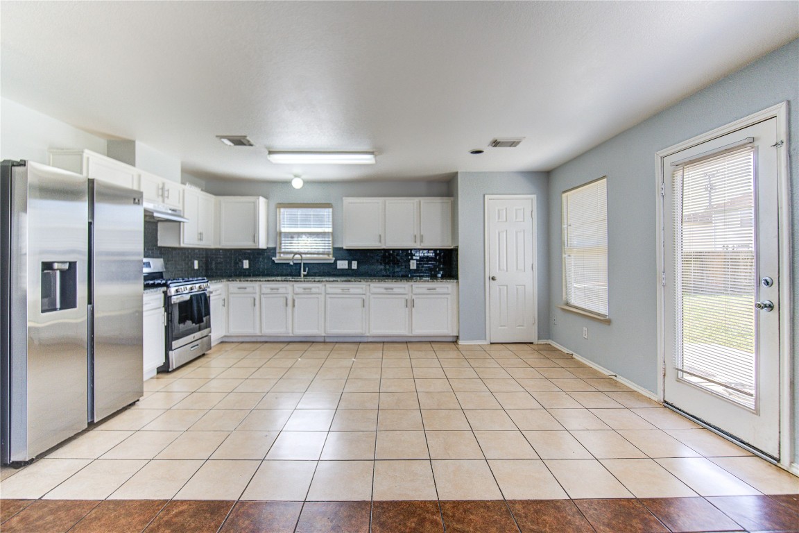 22919 Twisting Maple Court Spring, TX 77373 - Photo 20 of 49 a large kitchen with granite countertop a stove a sink a refrigerator a counter top space and cabinets