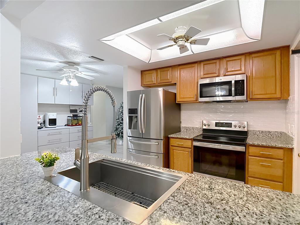 9171 Vicksburg Road Spring Hill, FL 34608 - Photo 13 of 55 a kitchen with stainless steel appliances granite countertop a stove a sink and a microwave