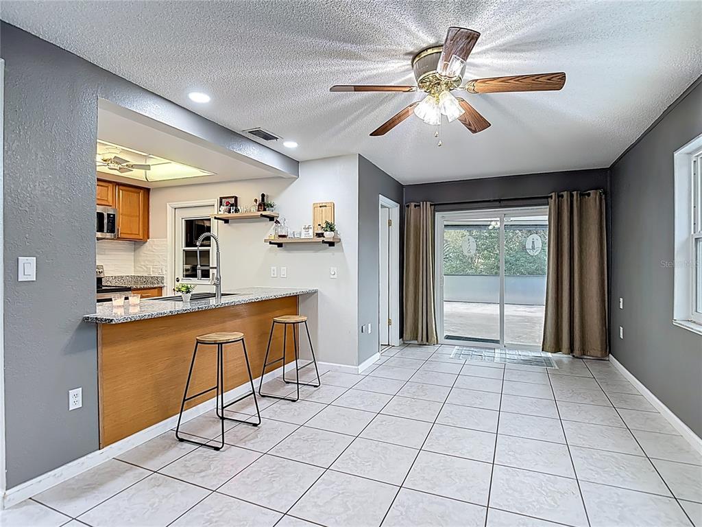 9171 Vicksburg Road Spring Hill, FL 34608 - Photo 14 of 55 a large kitchen with kitchen island granite countertop a refrigerator a sink dishwasher a dining table and chairs with wooden floor