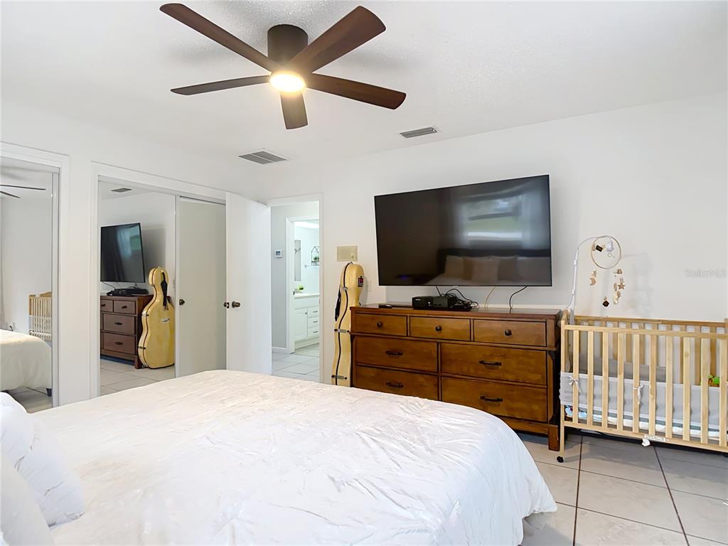 9171 Vicksburg Road Spring Hill, FL 34608 - Photo 21 of 55 a bedroom with a bed and a flat tv screen on dresser