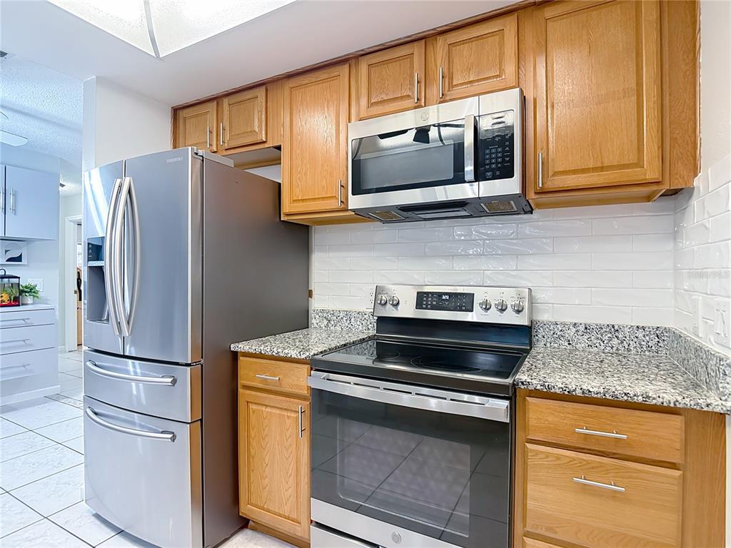 9171 Vicksburg Road Spring Hill, FL 34608 - Photo 10 of 55 a kitchen with stainless steel appliances granite countertop a stove microwave and refrigerator