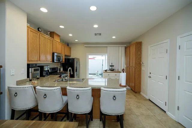 a large kitchen with a table chairs refrigerator and cabinets